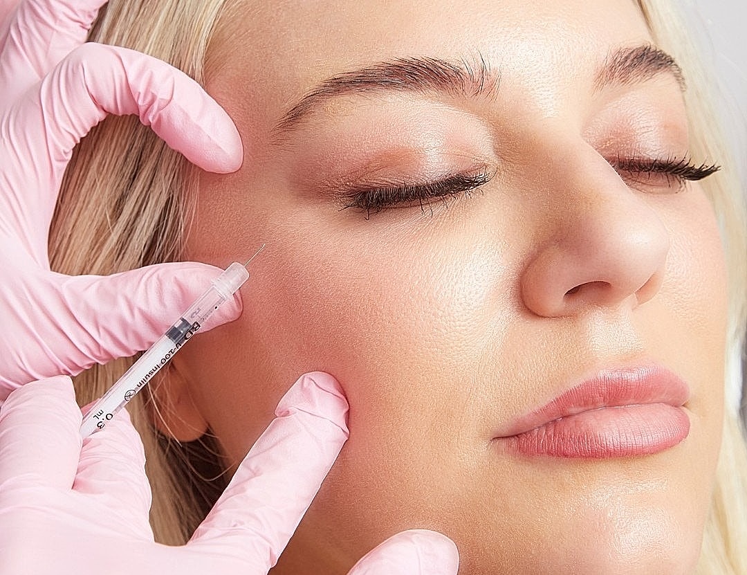 Administering injectable treatment on a woman's face.