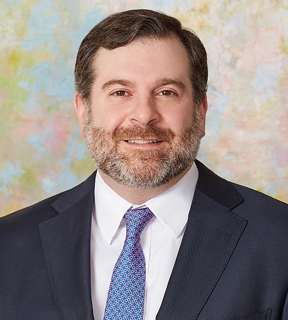 Smiling man in suit against pastel background.