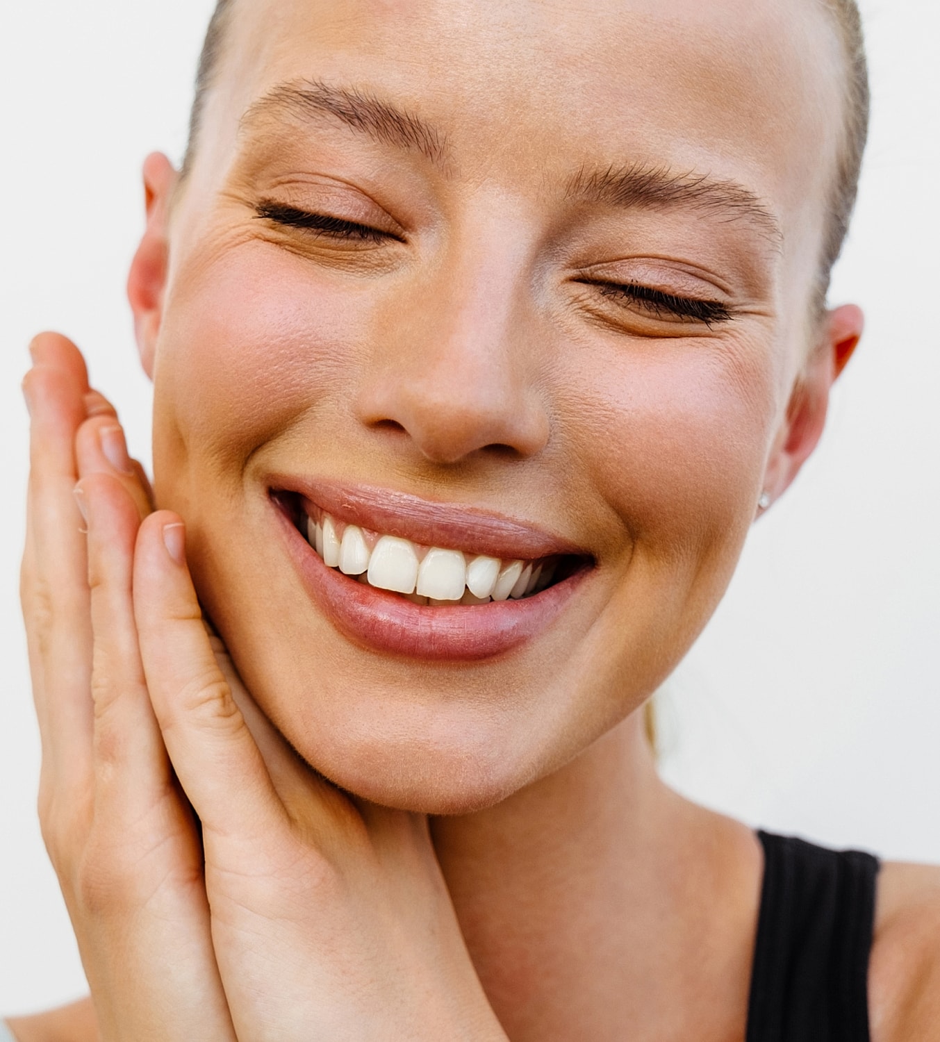 Smiling woman with hands on her face.
