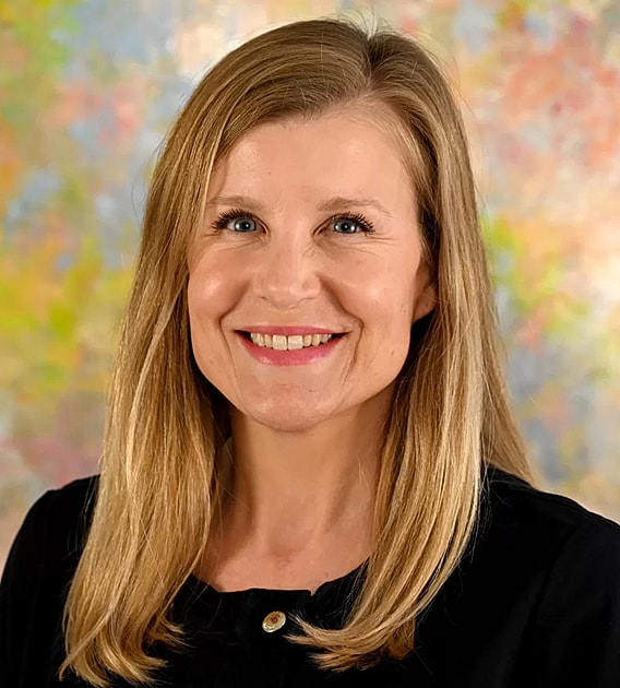 Smiling woman with long blonde hair, colorful background.