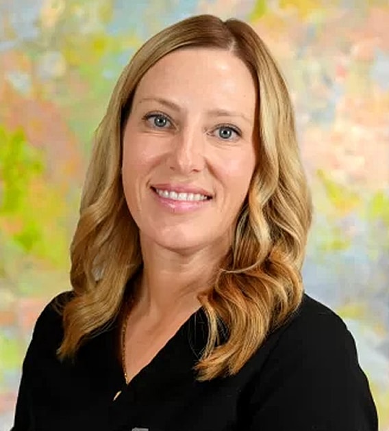 Smiling woman with wavy hair in front of art