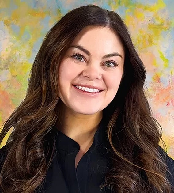 Smiling woman with long, dark hair and colorful background.