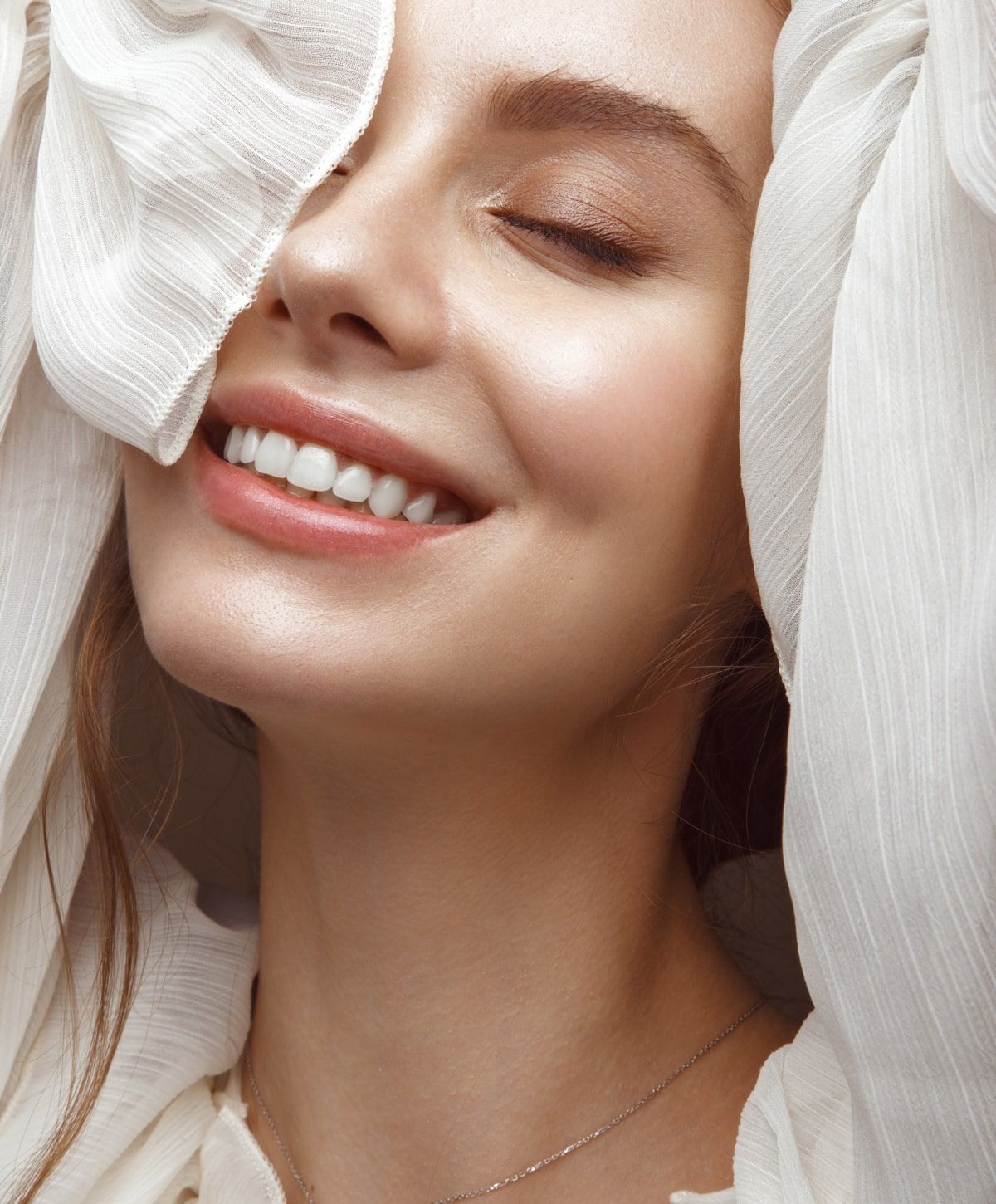 Smiling woman with soft, textured fabric draped.