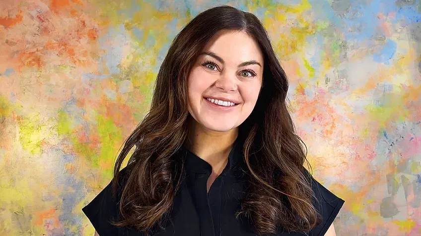 Smiling woman in front of colorful background.