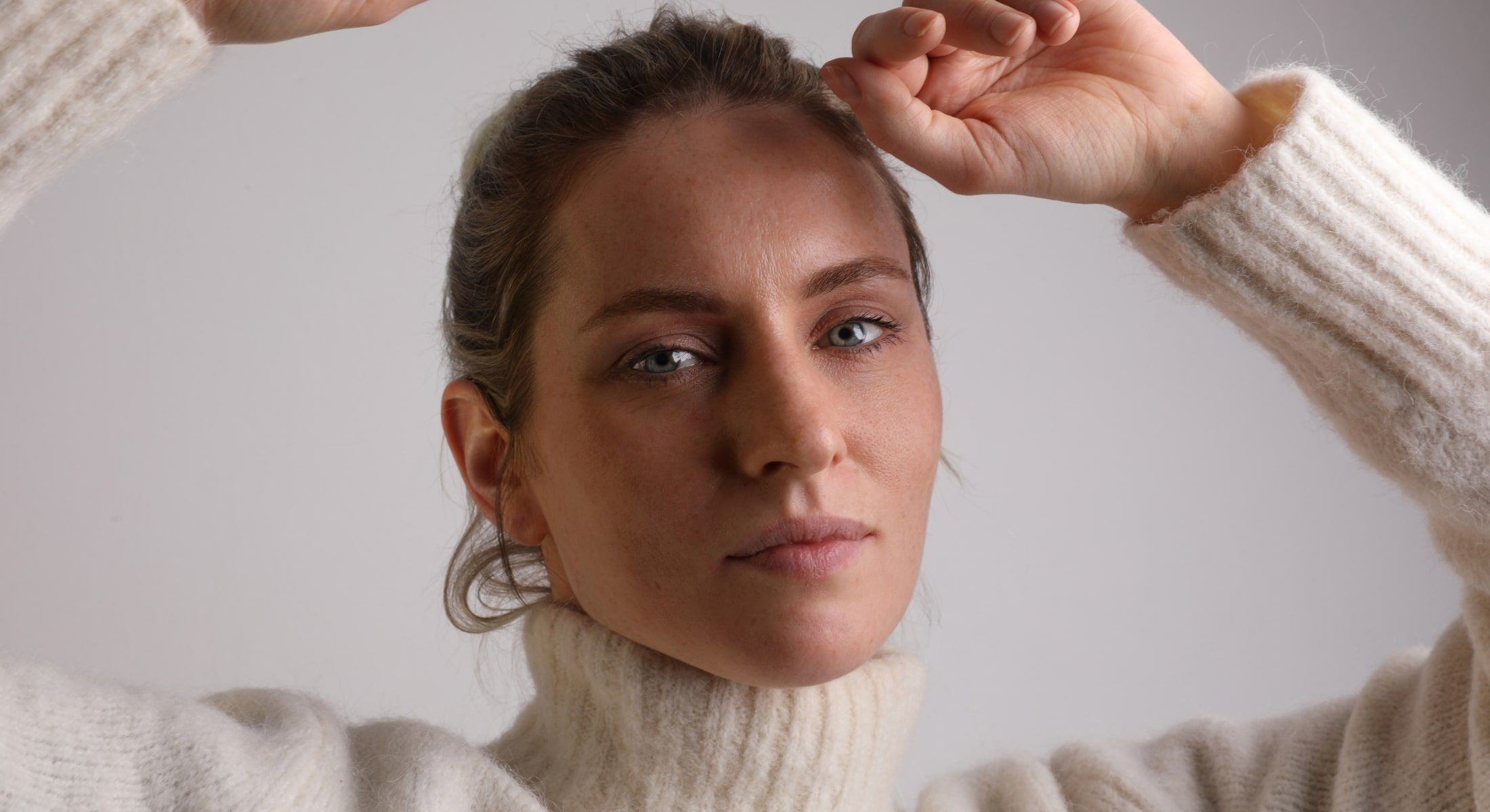 Woman in a cozy sweater with thoughtful expression.